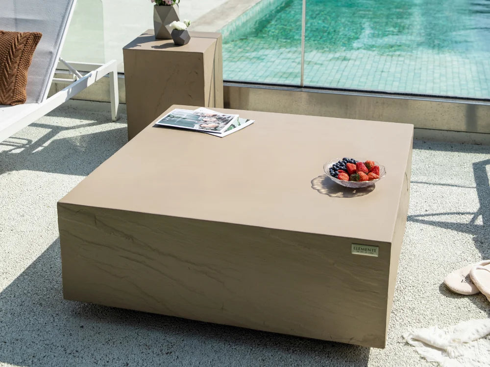 Colorado 34 inches Yellow Concrete Coffee Table, styled on a poolside patio with a bowl of strawberries and a magazine on top.