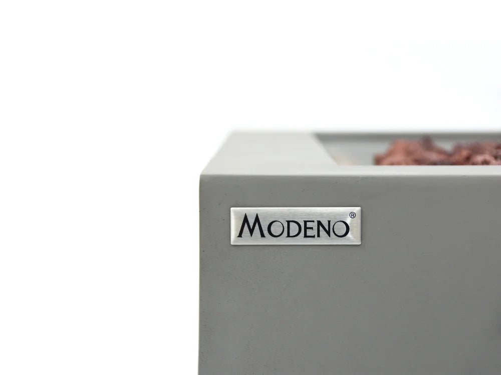 Close-up of Modeno Ridgefield Concrete Fire Table corner with a silver MODENO brand plaque on the front, against a white background.