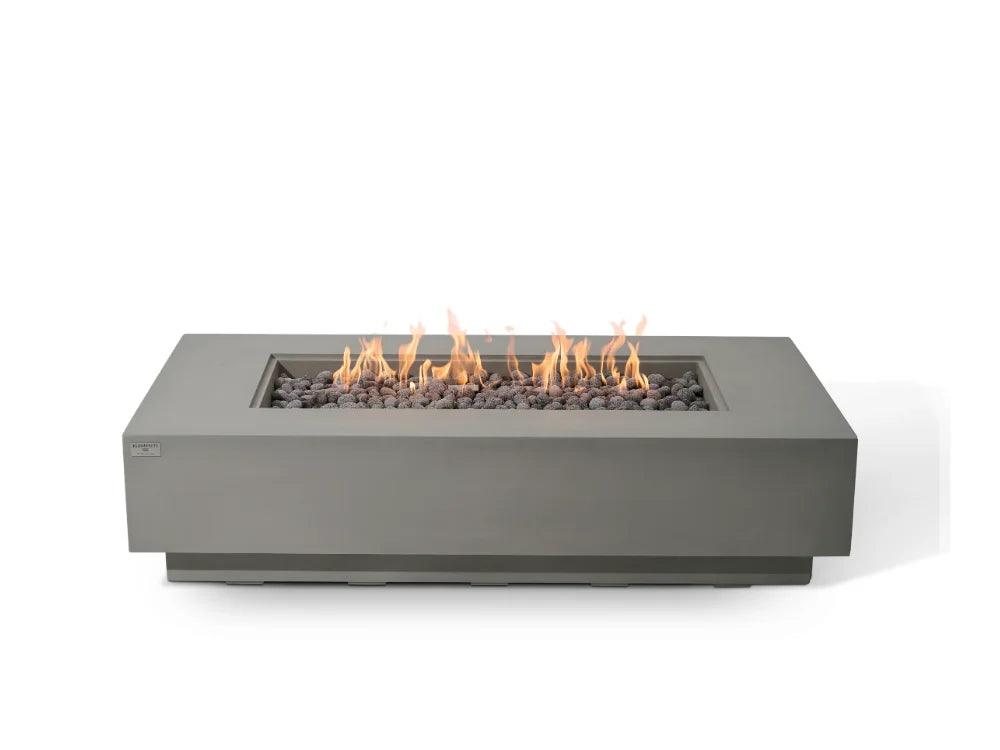 Elementi rectangular outdoor fire pit with a matte gray metal frame, filled with dark river rocks and active orange and yellow flames, shown against a solid white background.